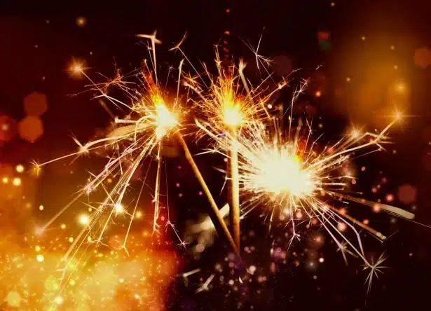 Lit sparklers on a red and orange background