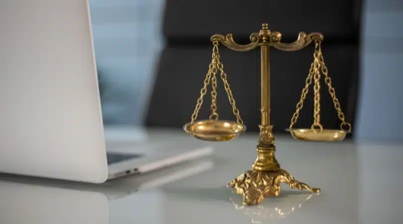 brass balance on a desk next to a laptop
