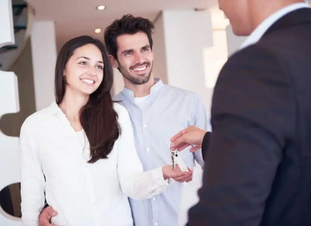 landlord passing house keys to two new tenants