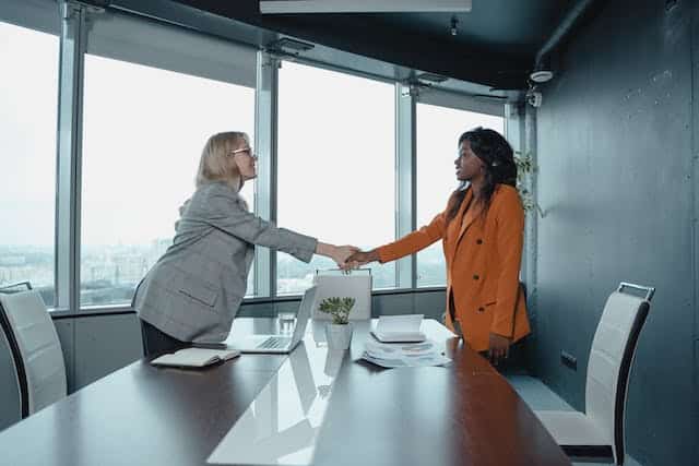 Two people shaking hands over a table