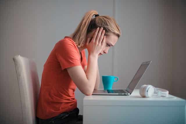A person stressed at their laptop.